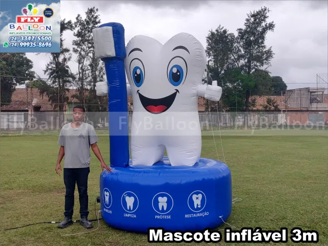Mascote inflável promocional dente com escova, personalizado, 3m, dente branco sorridente com escova azul sobre base azul com ícones de odontologia